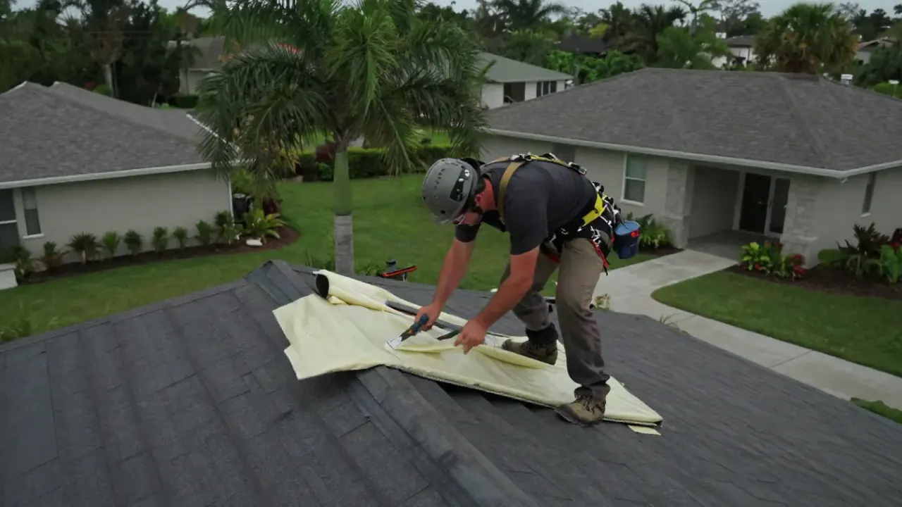 Roof Insulation Repair in Sunrise: roofer inside an attic is using a utility knife to trim a piece of radiant barrier